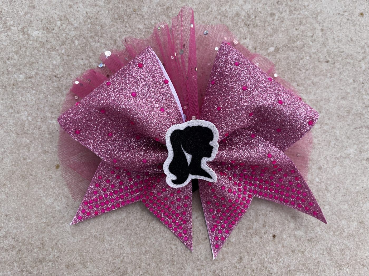 Pinke Glitzer-Schleife mit Tüll und einer schwarzen Silhouette in der Mitte